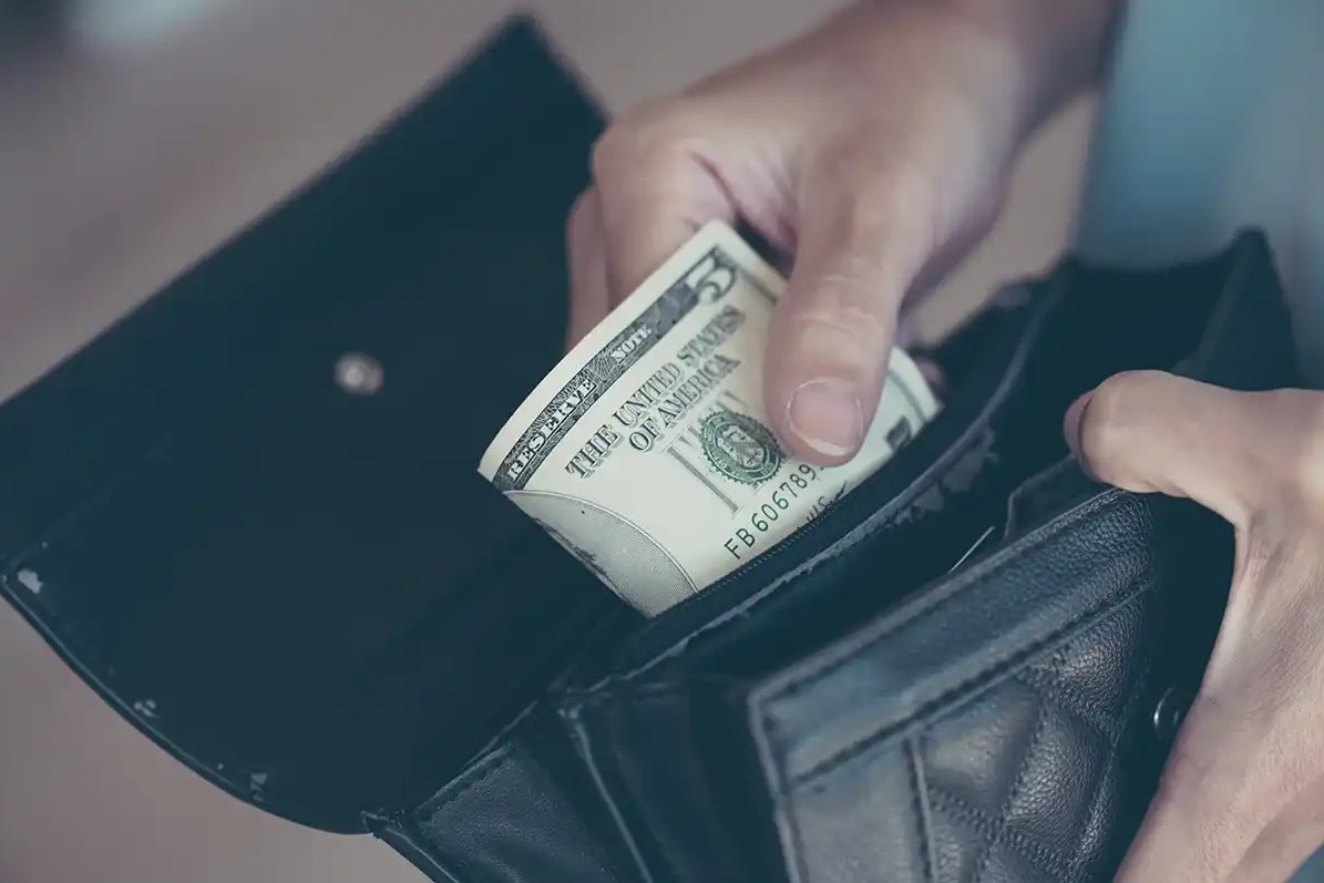 Someone saving $5 in their wallet