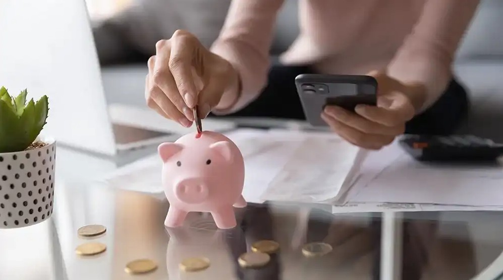 person depositing money into piggy bank