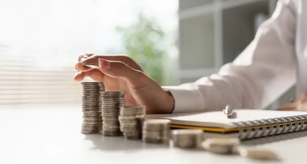 Someone stacking coins next to notebook