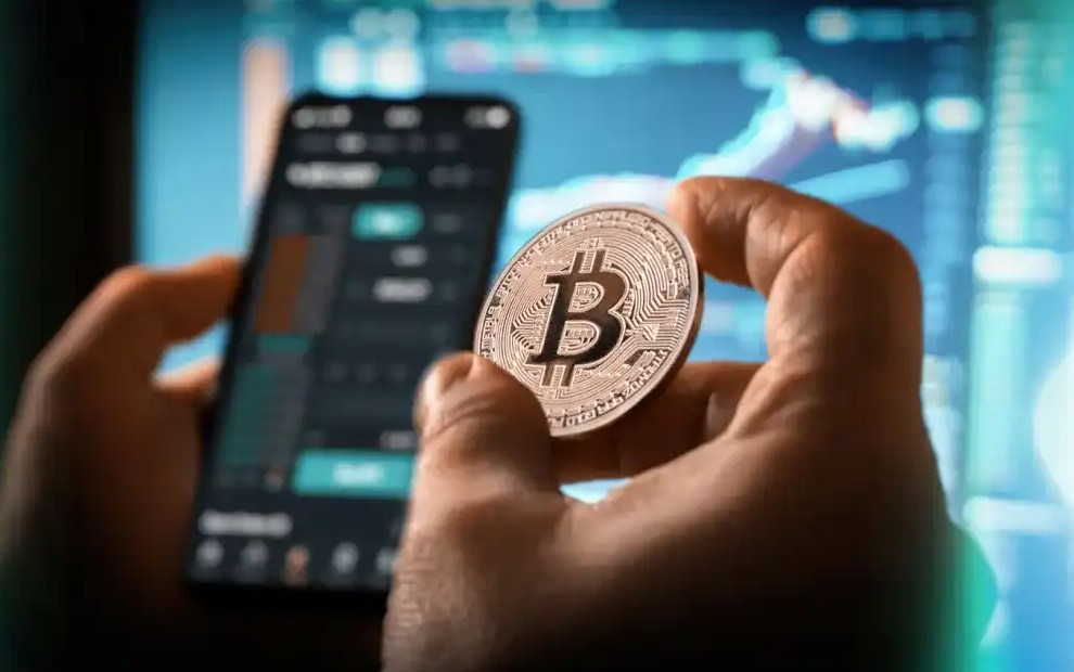 A person holding bitcoin next to phone