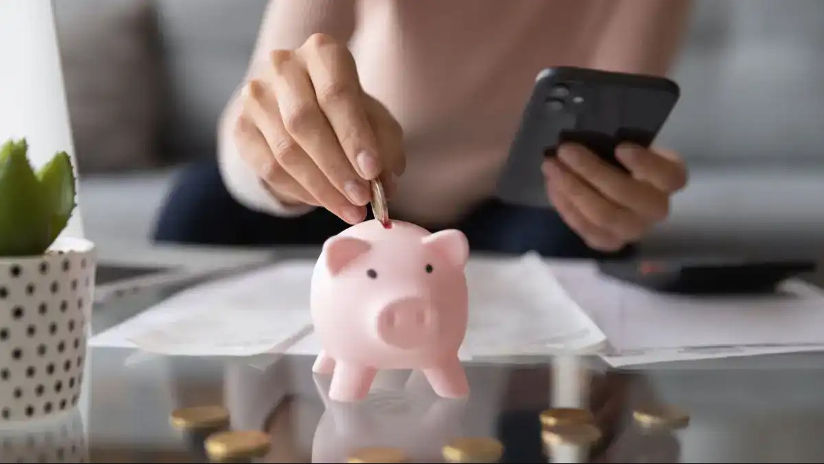 Person using money saving app to add money to piggy bank